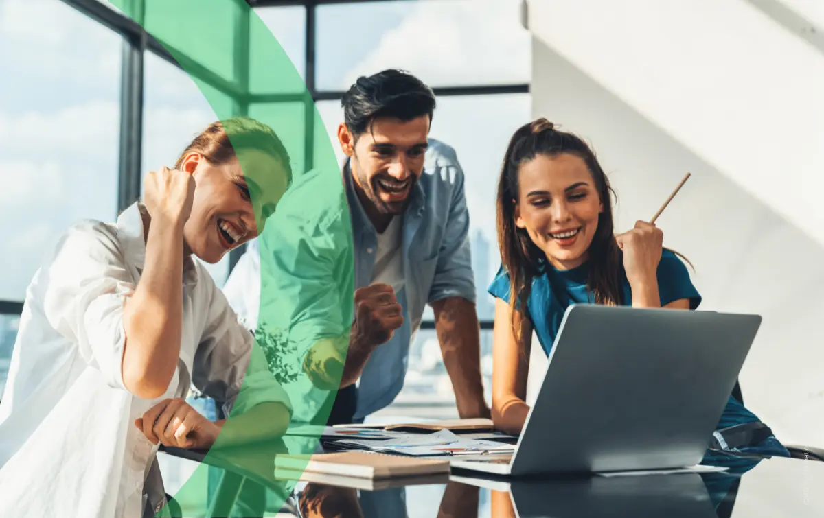 Team of three people laughing and happy in front of laptop